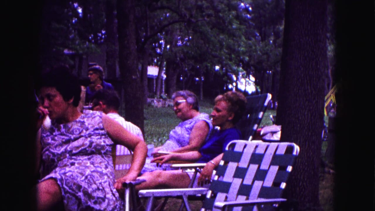 Women sit in woven lawn chairs under tall trees in Galena, Illinois, in 1967 home-movie footage.