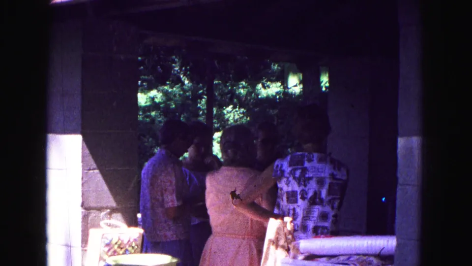 At the end of the clip, adults in summer clothes stand in deep porch shade at the 1967 Galena picnic, framed by columns and film borders.