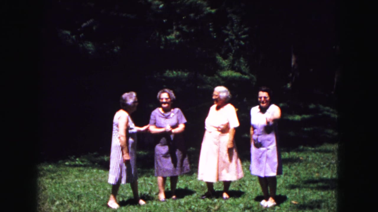In metadata-supported 1967 Galena, Illinois footage, four older women in summer dresses stand on grass under trees before posing together.