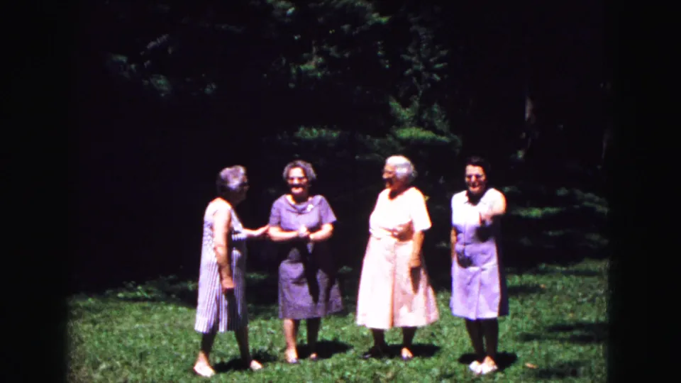 In metadata-supported 1967 Galena, Illinois footage, four older women in summer dresses stand on grass under trees before posing together.