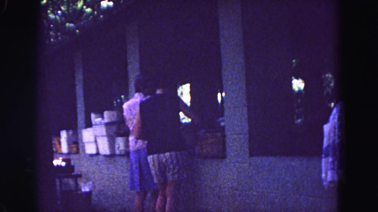 Several women stand near boxes under a covered outdoor area.