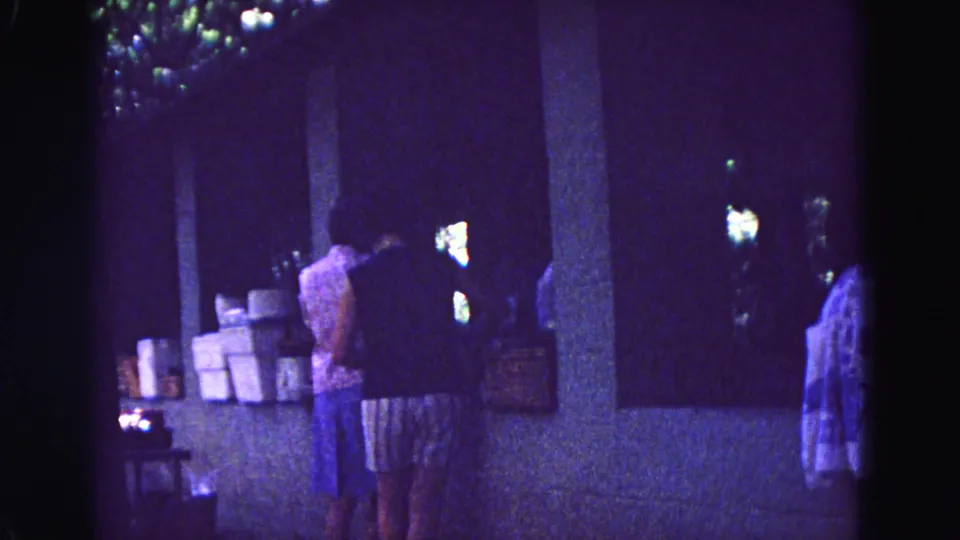 A soft, blue-tinted 8mm frame shows women beside boxes at a covered counter in 1967 Galena, Illinois.