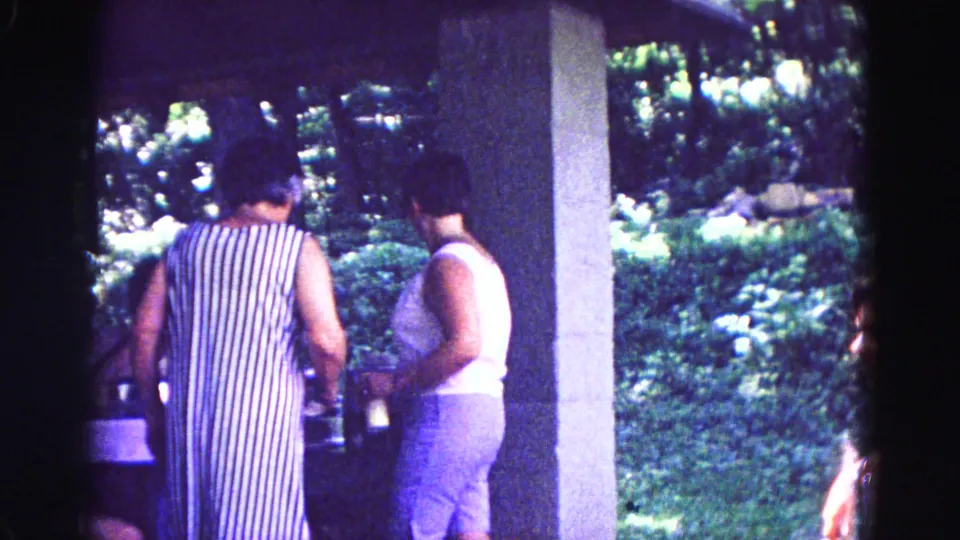 Two women stand with their backs to the camera at a covered counter, with garden greenery visible beyond in Galena, Illinois.