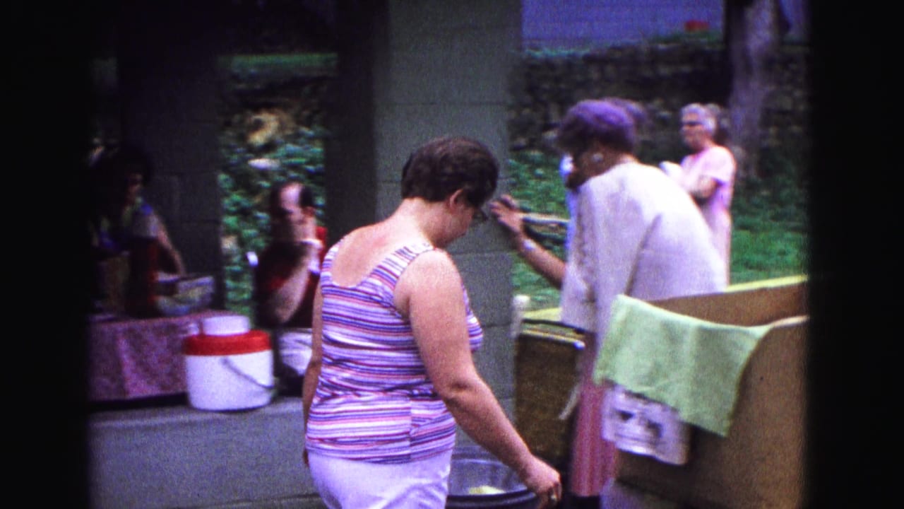 The woman moves through the Galena park pavilion as adults gather near a picnic table and stone wall in the background.