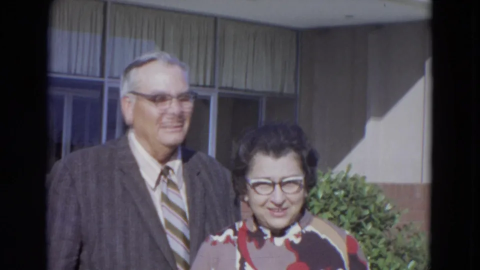 The couple remains close together in daylight outside a Lincoln, Nebraska building, with the man smiling and the woman looking forward.