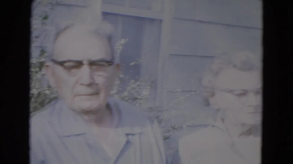 The final frame holds on an older man facing the camera with an older woman beside him near a sunlit building exterior in Lincoln, Nebraska.