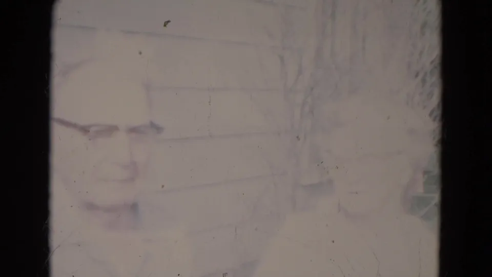 Faded final frame from the 1967 Lincoln home movie, with the couple barely visible through overexposure, dust, and film wear.