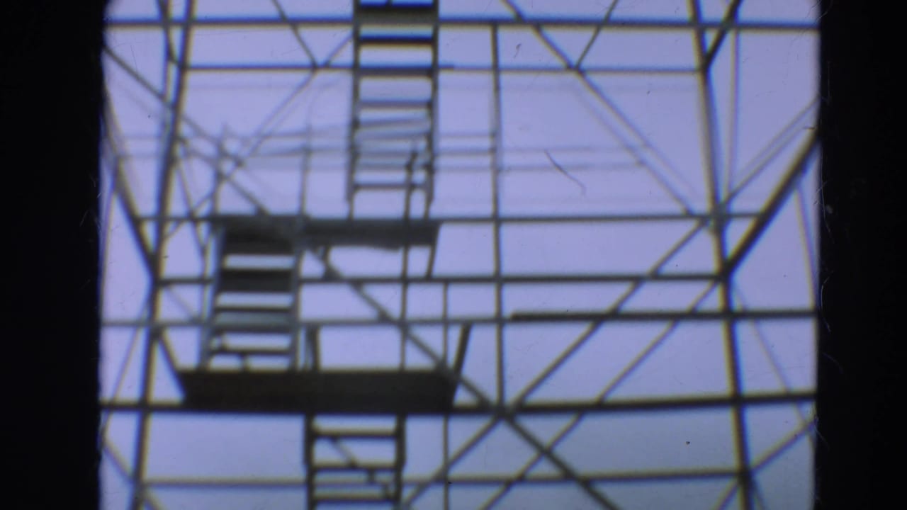 Low-angle view of steel tower stairs and cross-bracing against a pale sky.