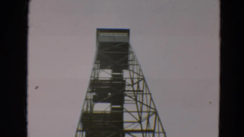1967 Minnesota 8mm frame showing the upper reach of a steel observation tower with open stairs and platforms.