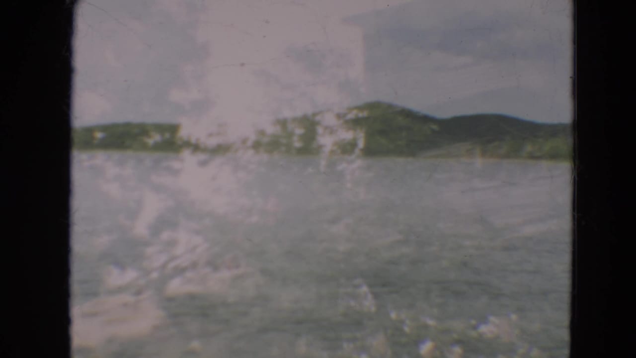 Blurred lake shoreline with hills and surface marks across the frame.