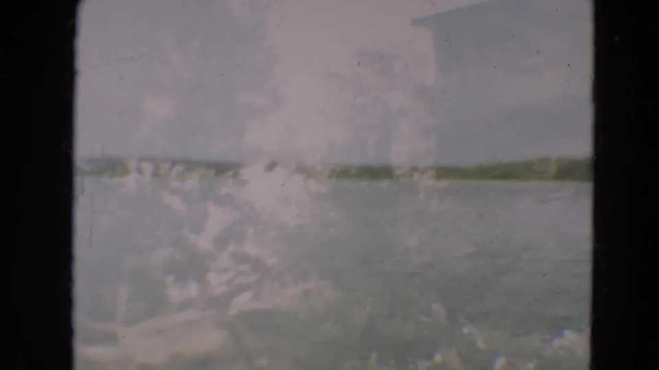1967 Minnesota 8mm lake landscape with a faint far shore, pale sky, muted water, and pronounced home-movie film wear.