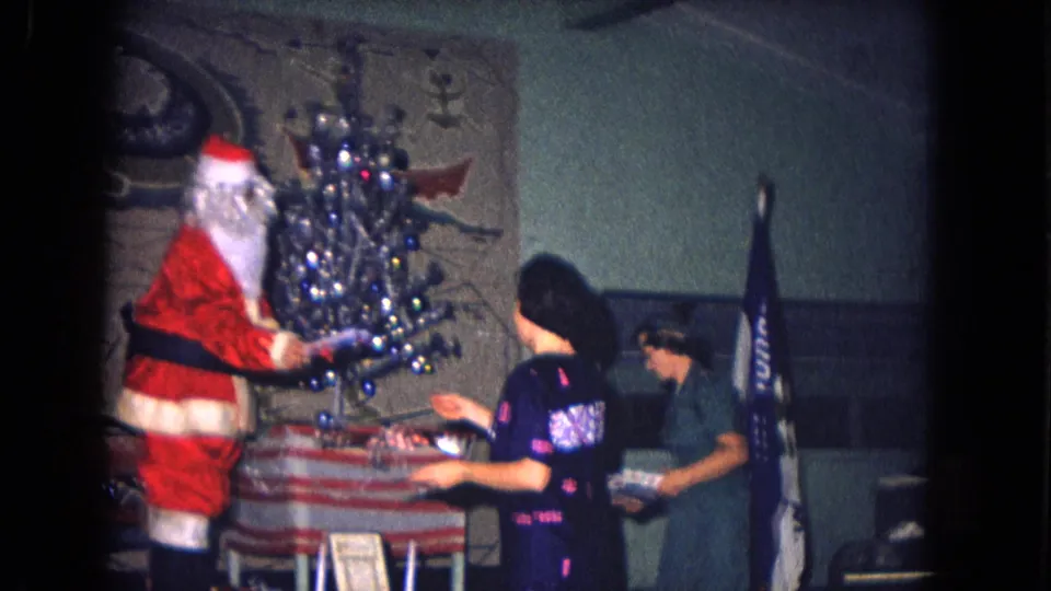 Santa Claus appears beside a small decorated Christmas tree at a 1967 New Mexico military holiday gathering.