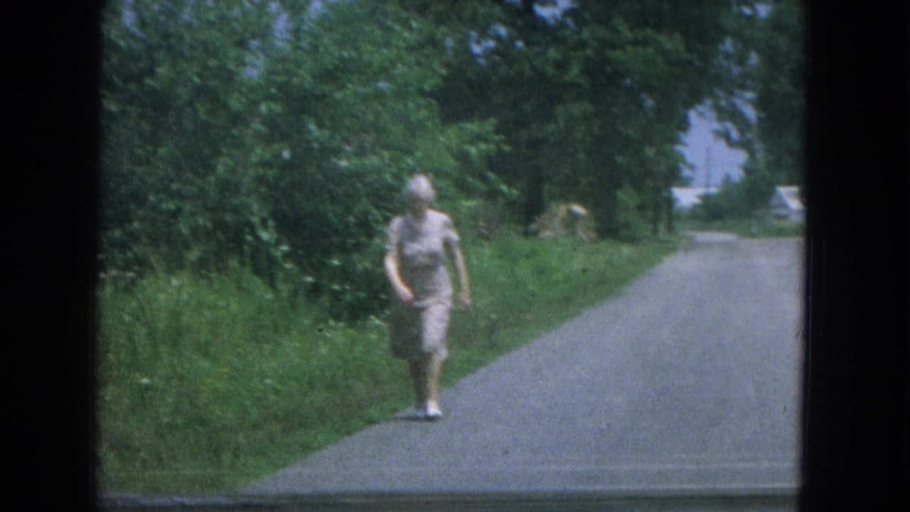 The woman continues along the rural New Mexico road, framed by dense greenery and filmed from a moving vehicle perspective.