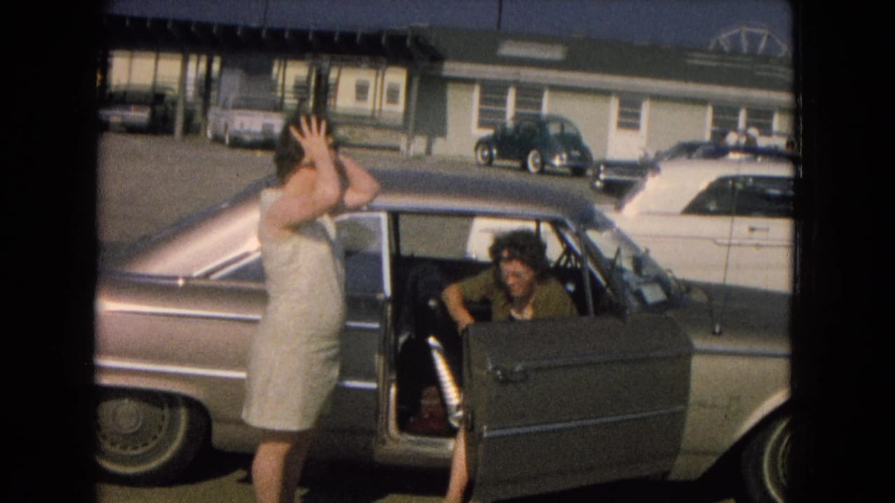A woman adjusts her hair beside an open classic sedan door, with another adult visible in the front seat.