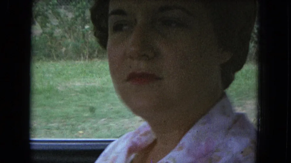 A close view shows the woman beside a car window, with grass and trees outside, likely in New Mexico home-movie footage.