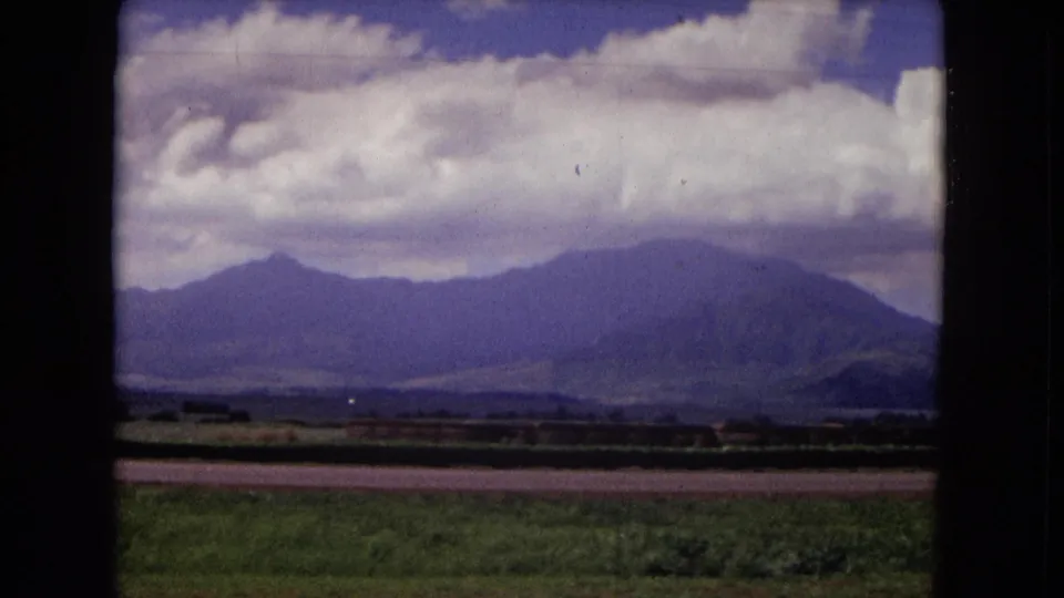 1967 New Mexico 8mm frame focused on open fields, distant mountains, and a heavy band of white cloud across the sky.