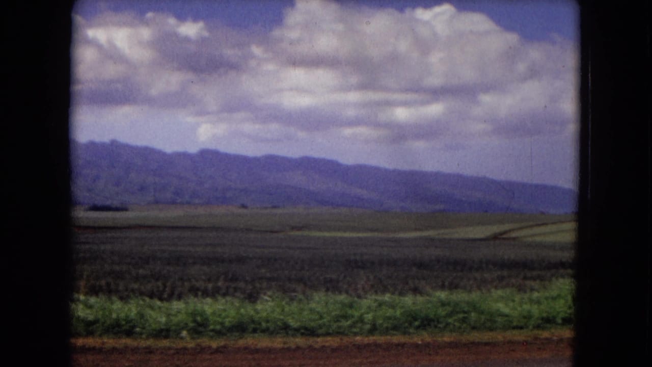 Flat fields and a mountain range appear under layered clouds.