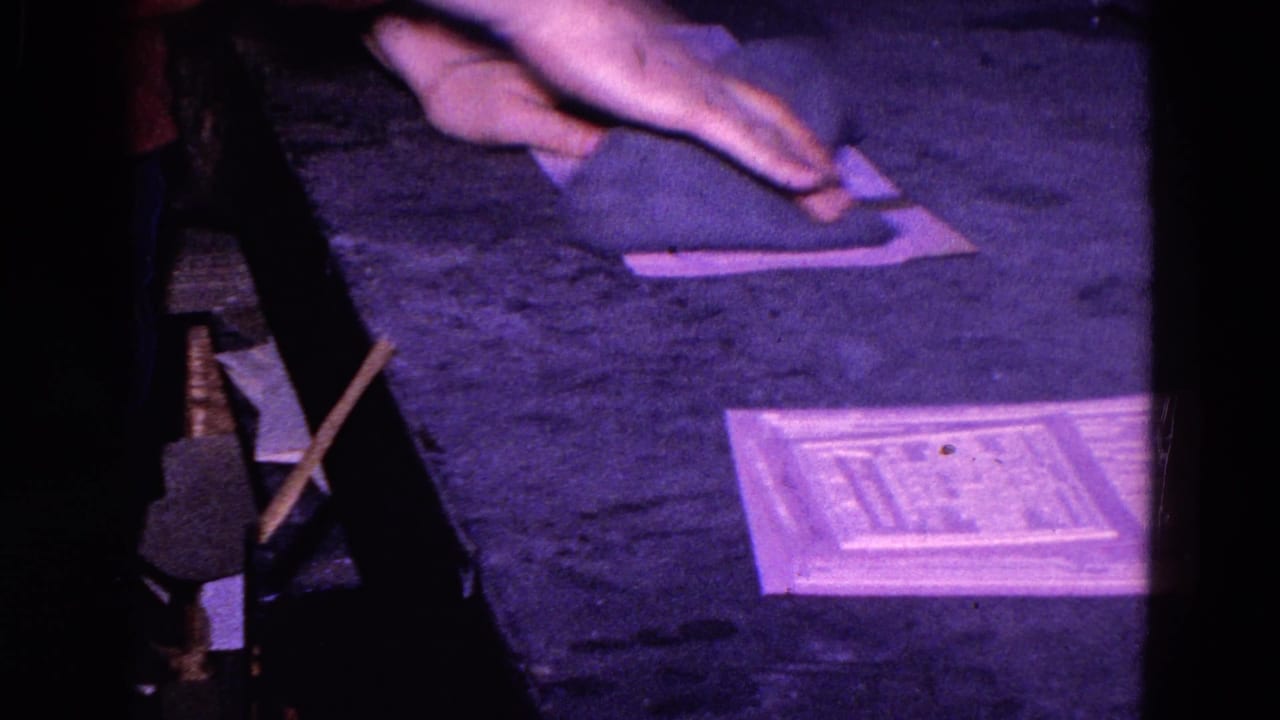 A hand presses a dark cloth against papers on a tabletop.