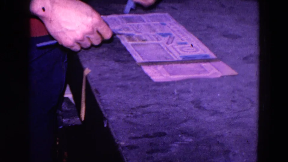 The final frame shows a hand holding a printed paper template above another sheet, with the person partly visible from the torso down.