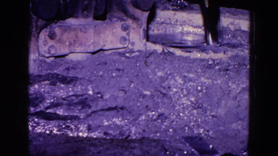 1967 Trenton factory footage frame with metal components, gritty floor texture, and dark 8mm frame borders.