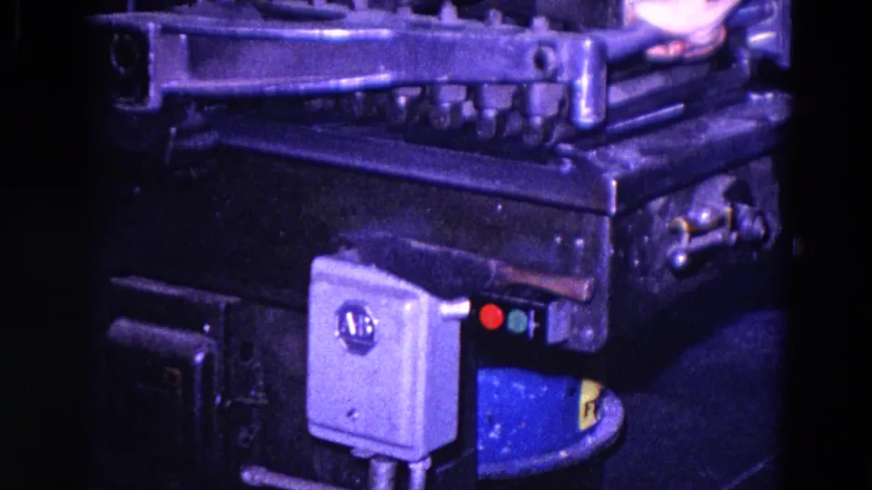 The machine's metal controls and side-mounted electrical box fill the frame while the operator's hand remains partly visible above.