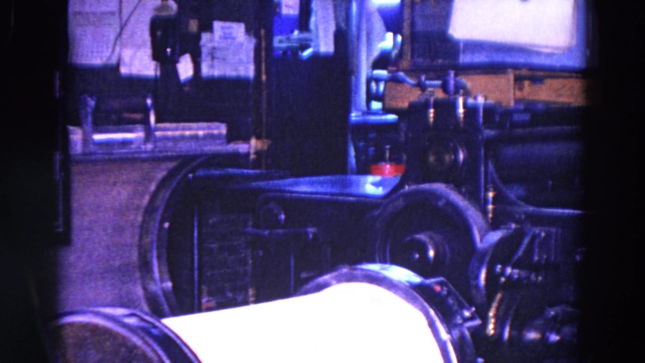 1967 Trenton workshop interior with dark industrial machinery, a roller-like form, and a metal table under blue-purple film color shift.
