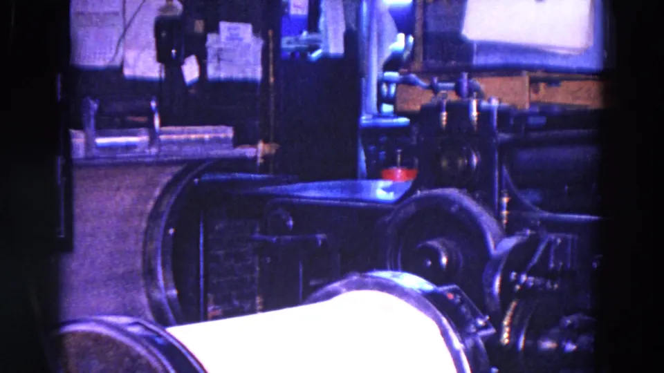 1967 Trenton workshop interior with dark industrial machinery, a roller-like form, and a metal table under blue-purple film color shift.