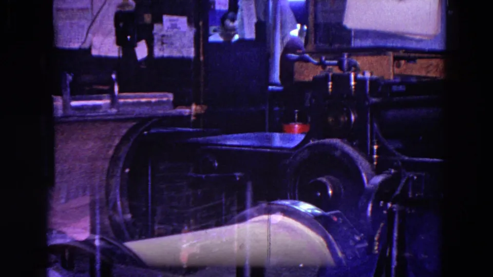A closer 8mm view shows the workshop machinery, metal work surface, and posted wall materials in the 1967 Trenton interior.