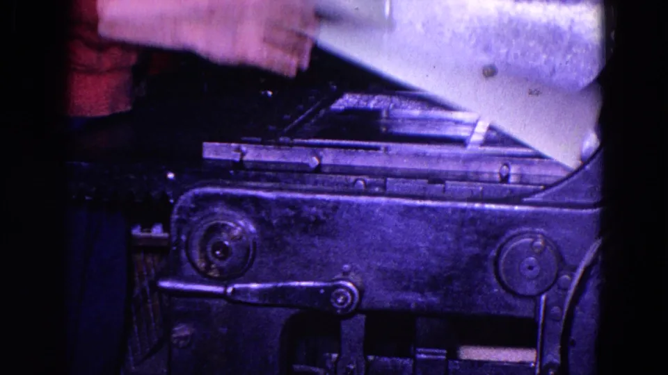 1967 Trenton 8mm frame showing a worker removing or lifting a light sheet from a metal industrial printing press.