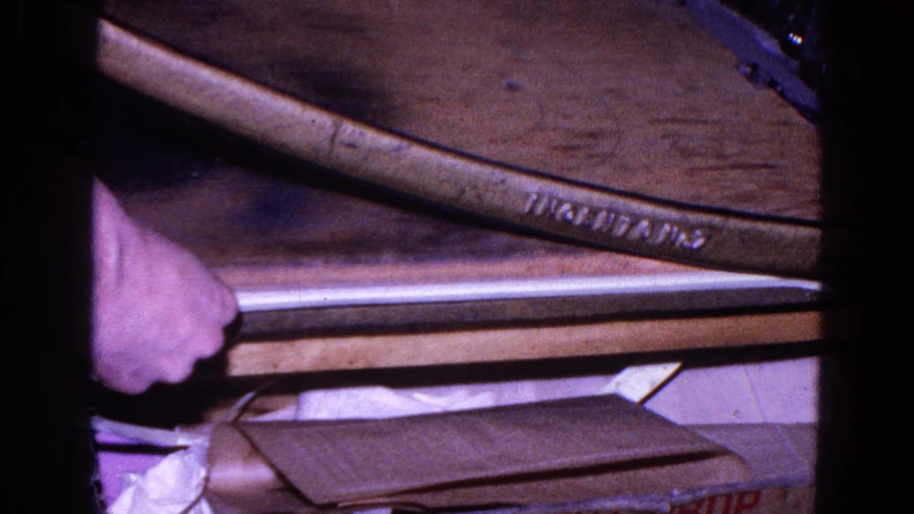 Worker's hand near a large paper cutter with stacked sheets on a wooden table.