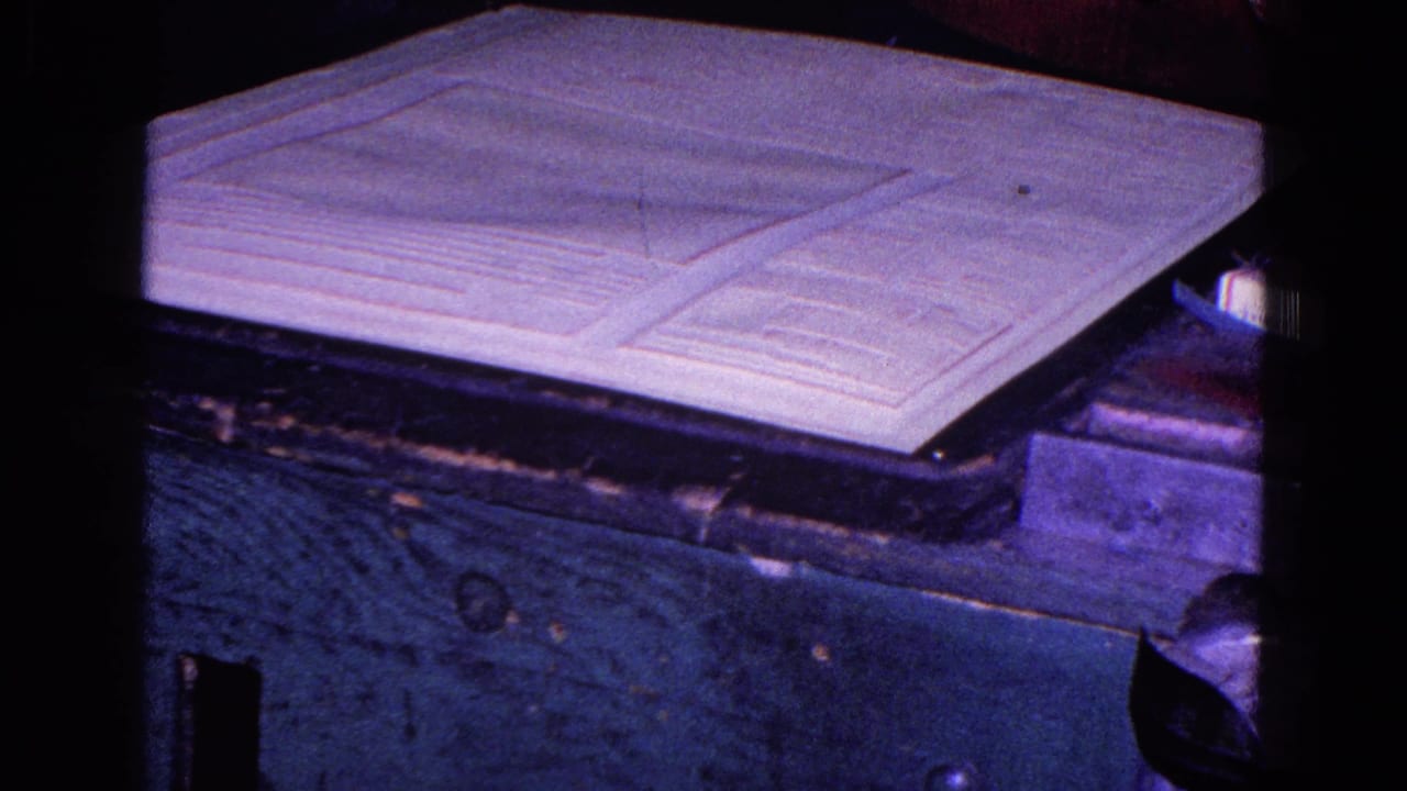 White fabric panel lying on a dark wooden surface under purple-tinted light.