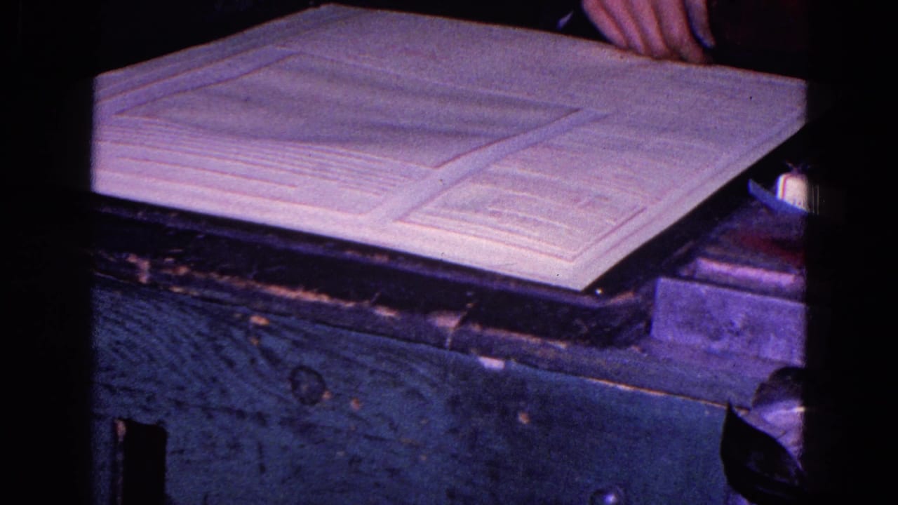 1967 Trenton home-movie frame showing white fabric on a work surface with a partial hand entering near the upper edge.