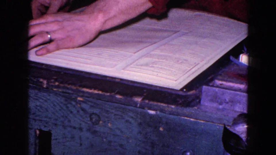 Close 8mm frame of a ringed hand over open desk documents, consistent with paperwork or bookkeeping activity.