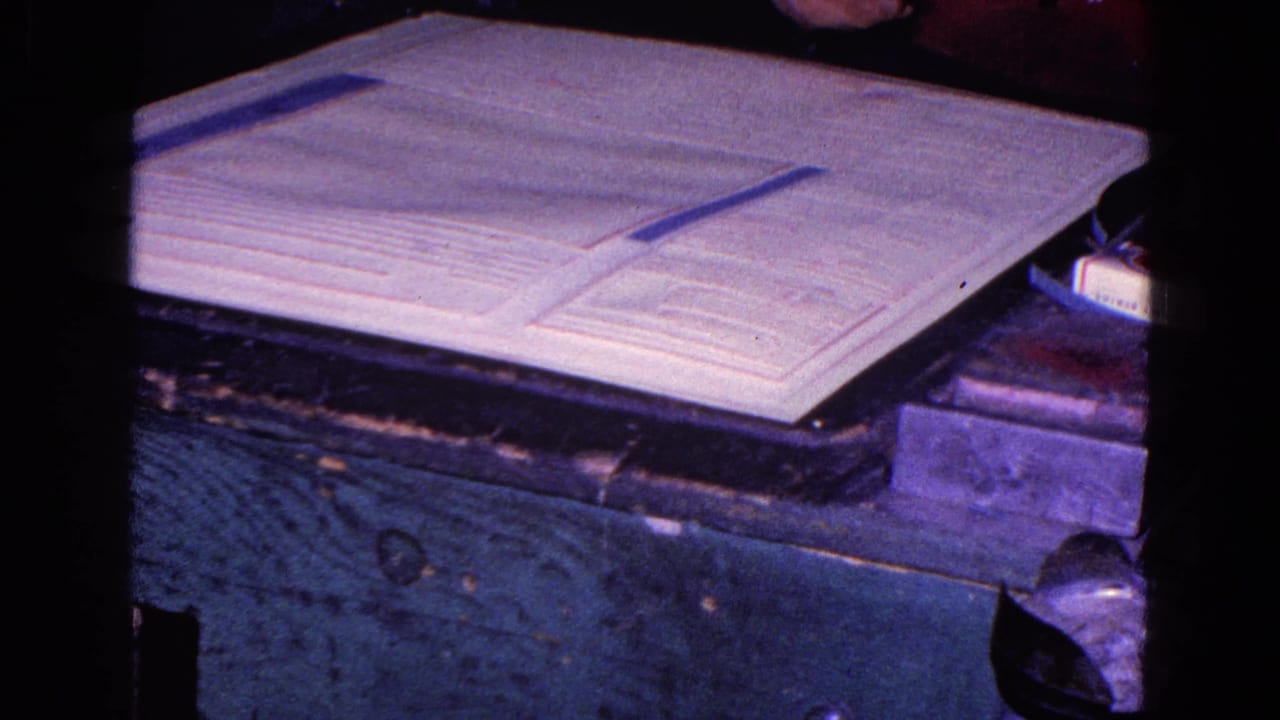 A large document lies on a dark table with a narrow strip across it.