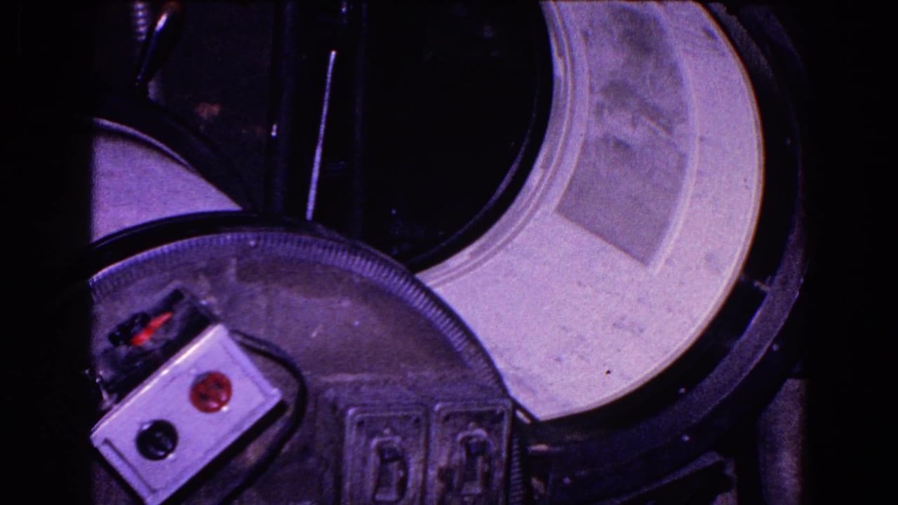 The paper sheet remains seated in the curved bed of the cylindrical printing press, with controls and dark machine housing visible.