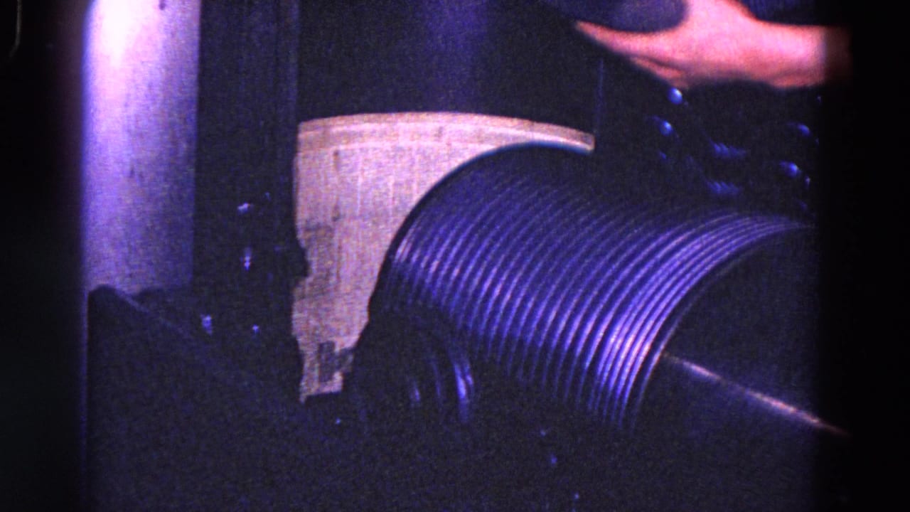 1967 Trenton machinery detail showing a ribbed cylinder, vertical pipe, pale panel, and partial operator arm.