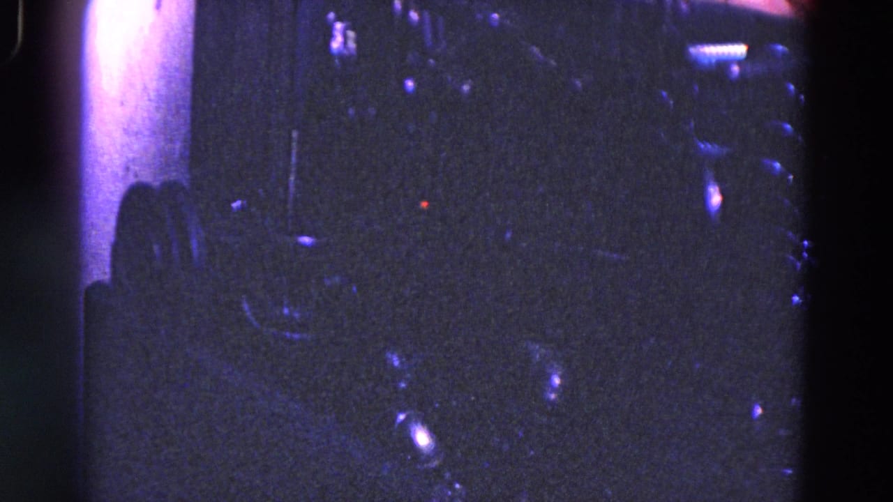 Close 8mm view of dark industrial machine components in Trenton, New Jersey, with reflective fittings and heavy purple-blue color shift.