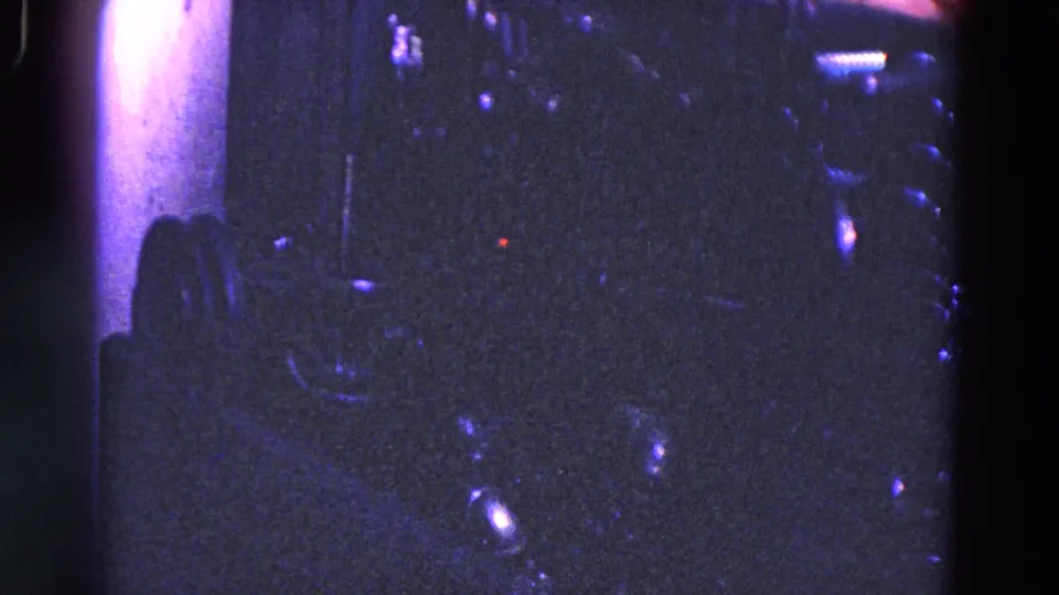 Close 8mm view of dark industrial machine components in Trenton, New Jersey, with reflective fittings and heavy purple-blue color shift.