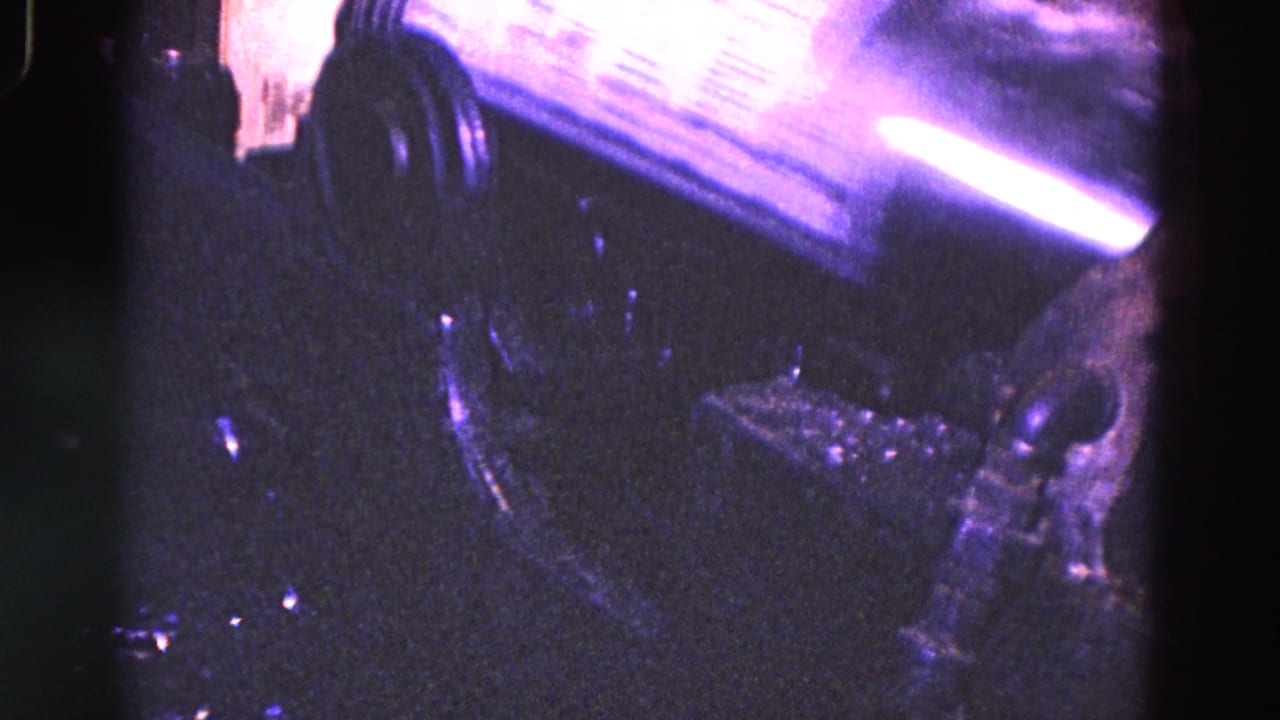 Reflective metal cylinder and surrounding dark machine parts seen in a close industrial view.