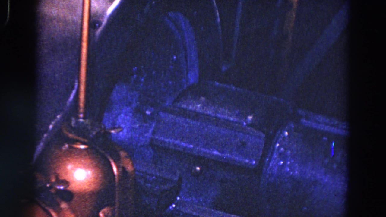 Blue-lit industrial machinery with a copper-colored round part and dark metal housings.
