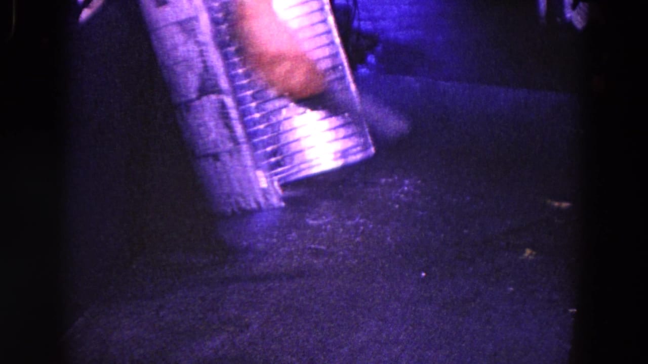 Close view of a hand and striped sleeve near a shiny metal object in a dark purple-tinted interior.