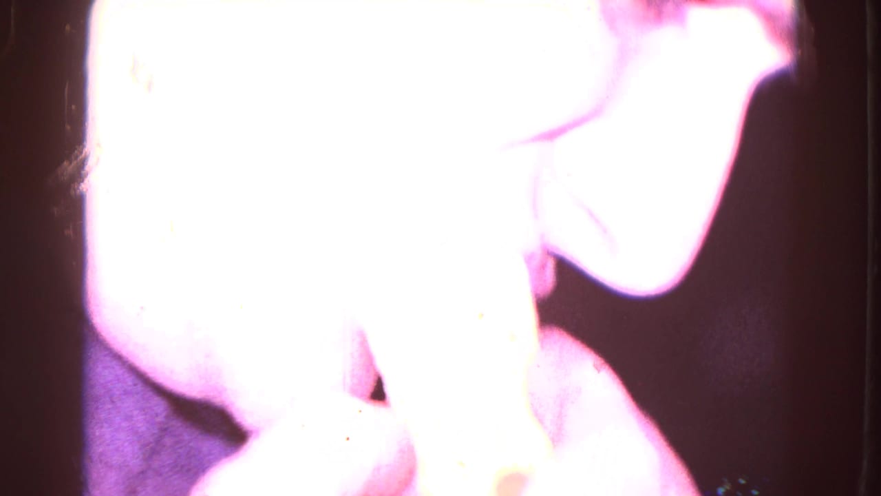 Overexposed close view of a man eating a sandwich inside a dark room.