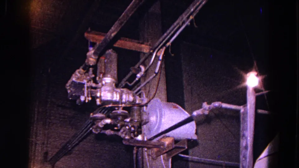 Final 1967 Trenton factory frame showing cable runs and metal electrical hardware under dim, blue-tinted 8mm exposure.