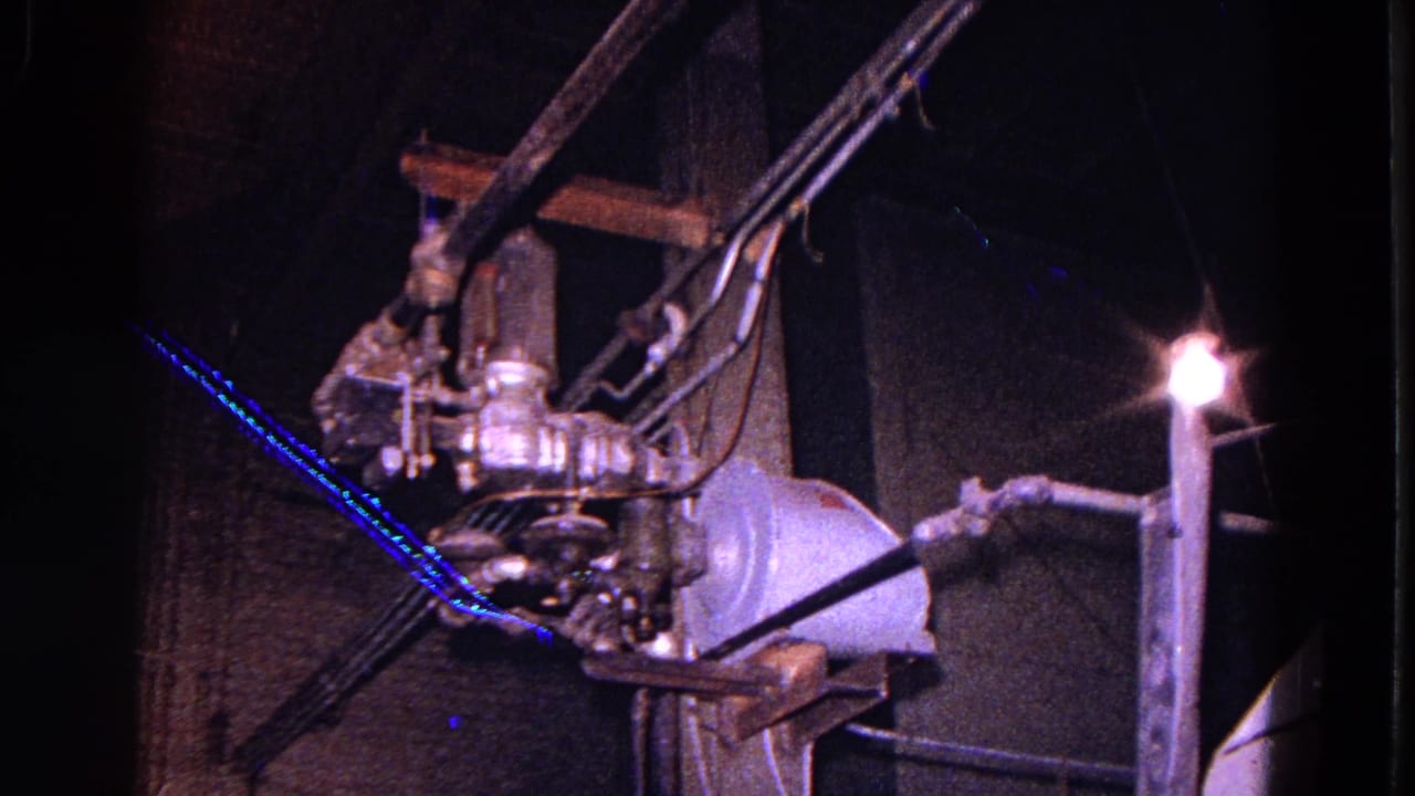 Industrial torch or welding equipment in a dim factory interior.