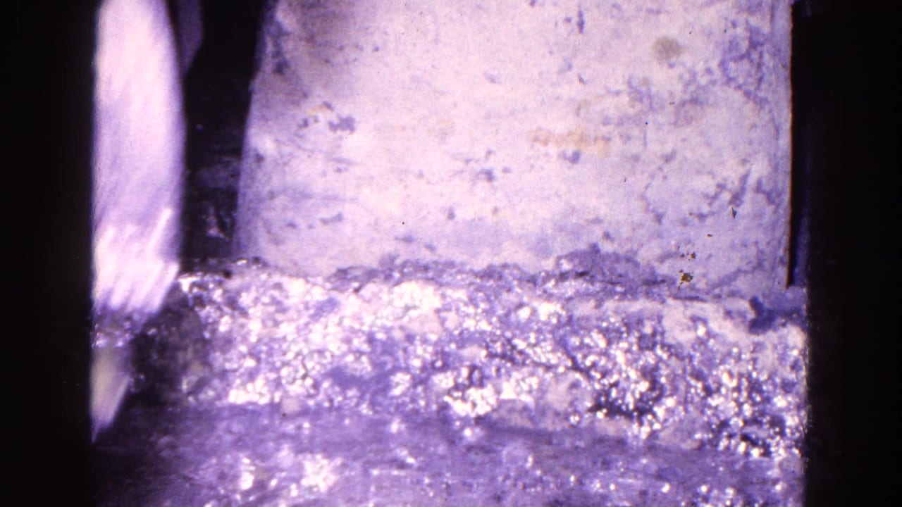 Close-up of a pale block beside shimmering liquid with a blurred object at the left edge.