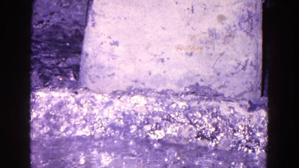 1967 Trenton 8mm close-up of a pale block over a bright, rippled liquid surface with heavy grain and purple tint.