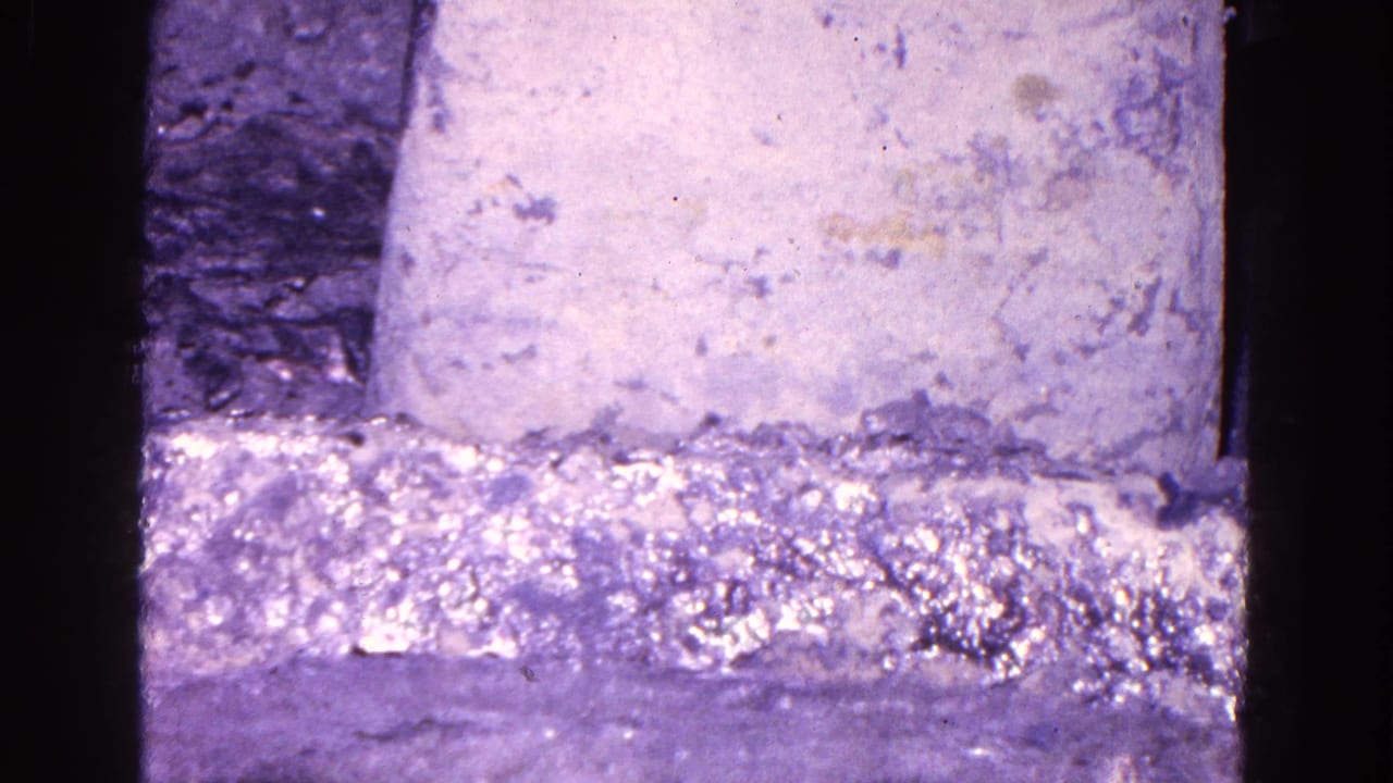 Close-up of a rough mold or industrial surface with purple-tinted film exposure.