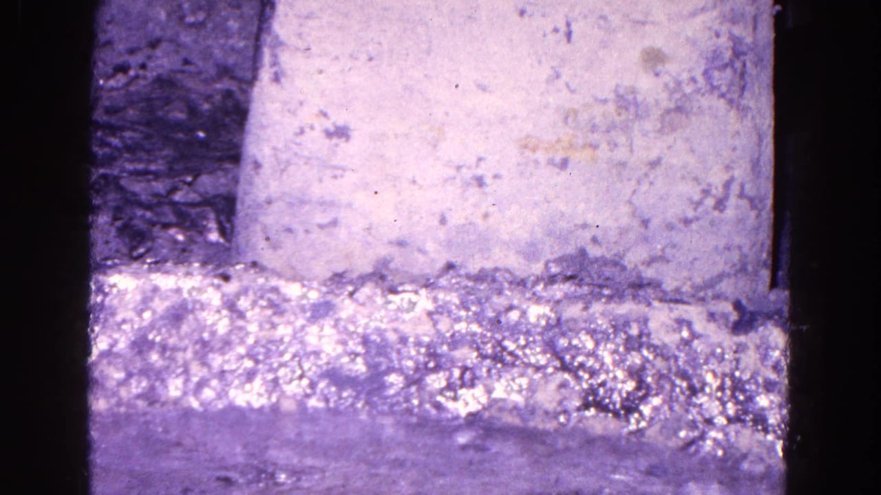 1967 Trenton industrial close-up with a rough mold surface, dark machinery edges, and purple-tinted 8mm film texture.