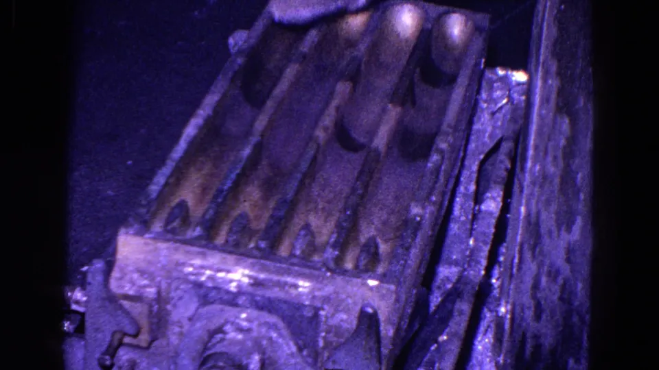 Close-up of a metal mold or die with rounded forms inside dark machinery, from 1967 Trenton 8mm industrial footage.