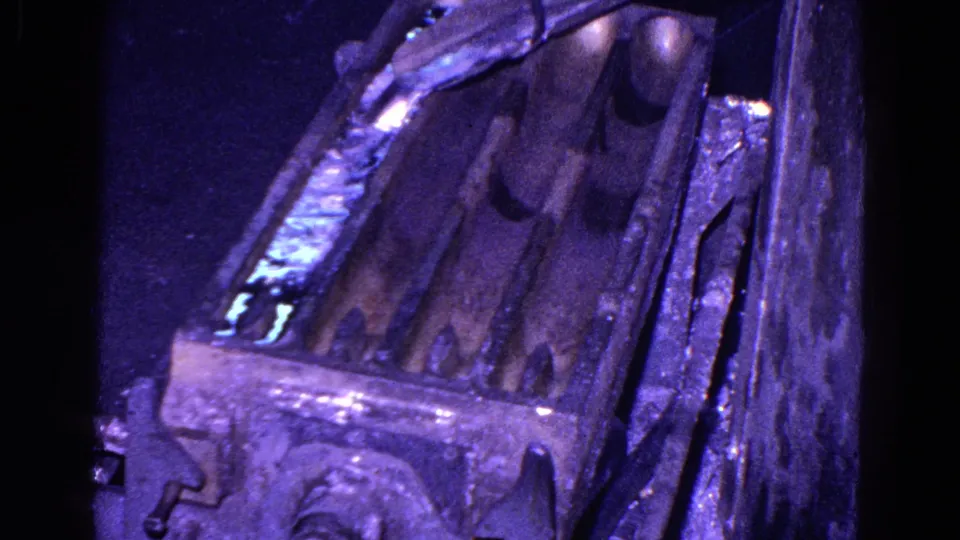 1967 Trenton 8mm frame showing shiny liquid in a metal chute, with dark adjacent troughs and weathered industrial surfaces.